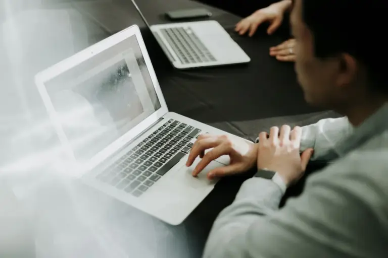 Person greift zum Laptop am Schreibtisch