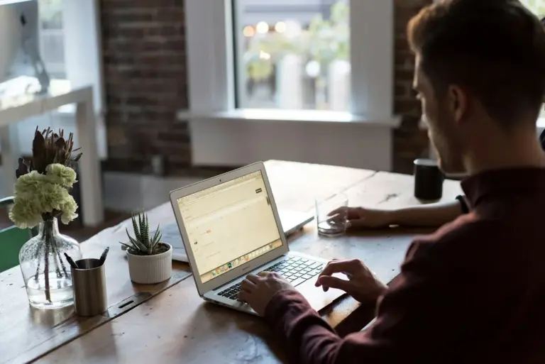 Person am Laptop mit einer Tasse Kaffee