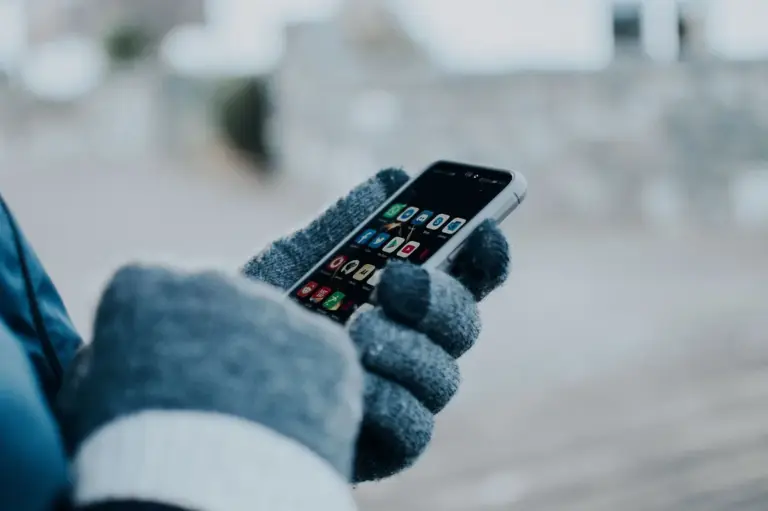 Hand mit Handschuh hält ein Smartphone und prüft den Zugang zum TikTok-Konto